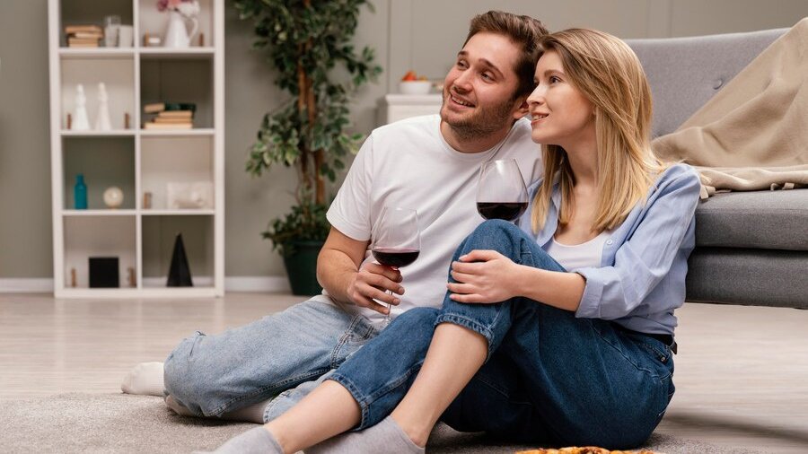 זוג צעיר עם פיצה וכוסות יין יושב על הרצפה וצופה בסרט זוג צעיר עם פיצה וכוסות יין יושב על הרצפה וצופה בסרט